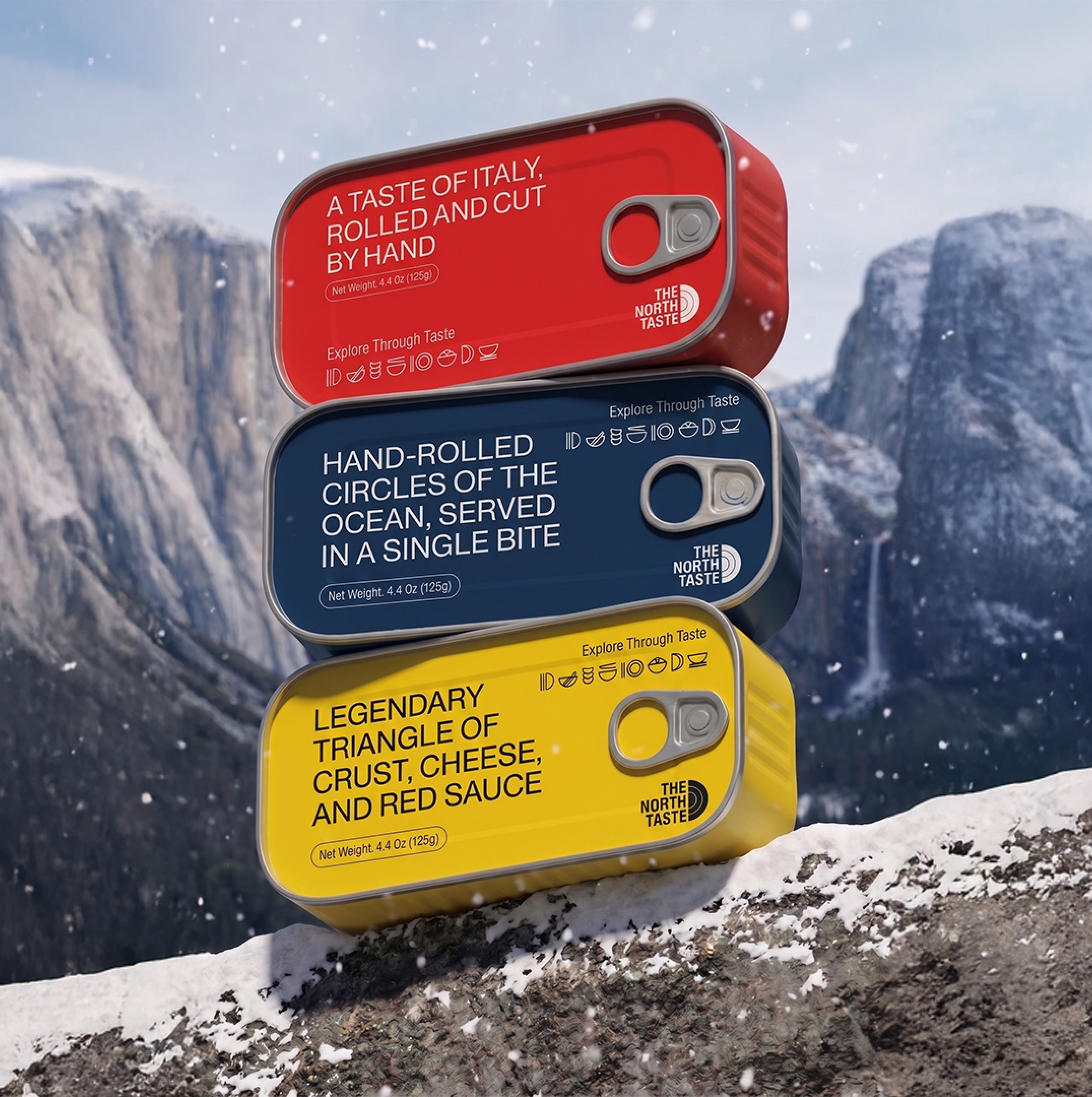 Three North Taste canned goods (red, navy, and yellow) resting on snowy mountain rocks